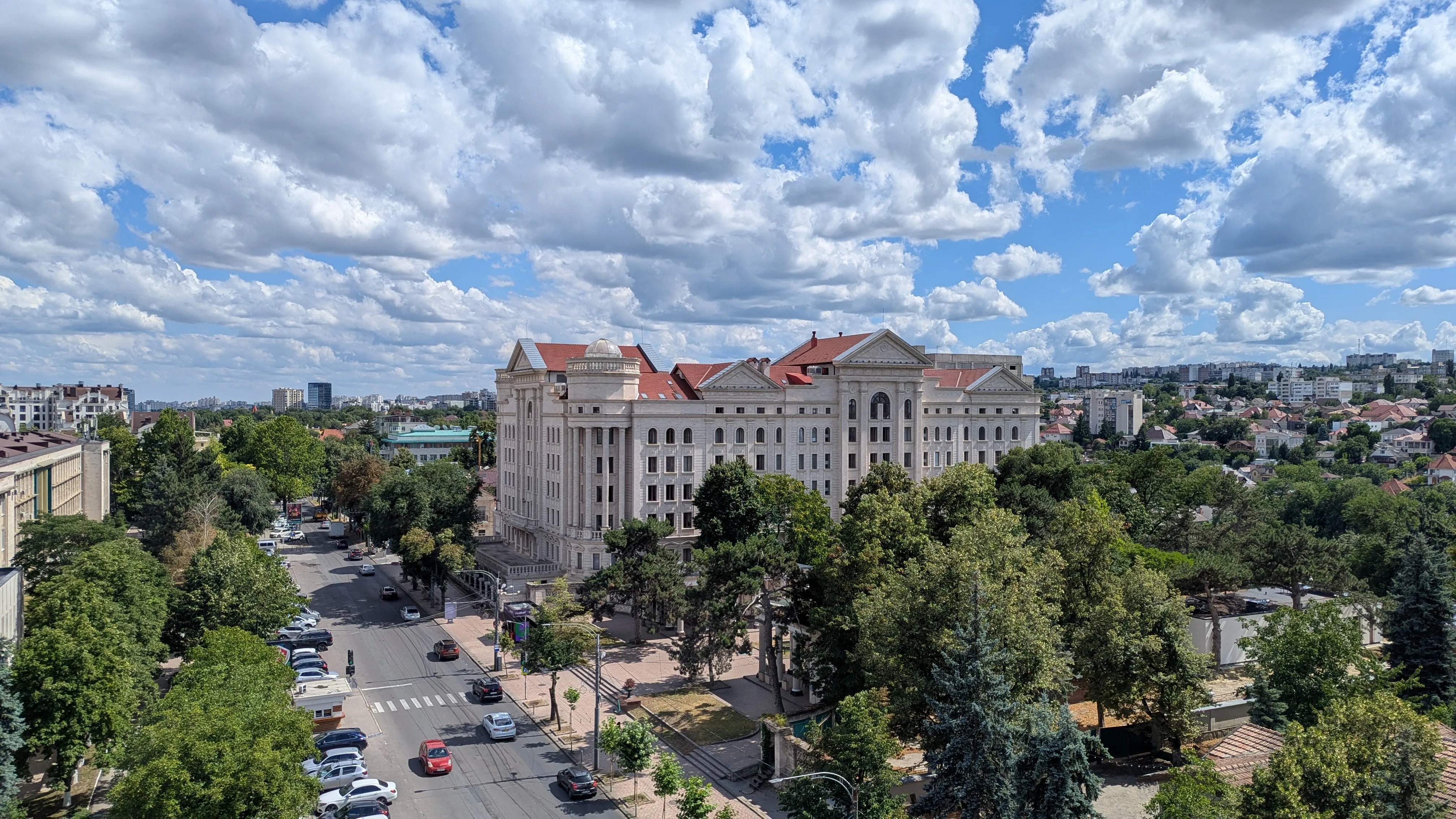 Panorama miasta, szeroka droga, duży budynek w klasycznym stylu, dużo zieleni