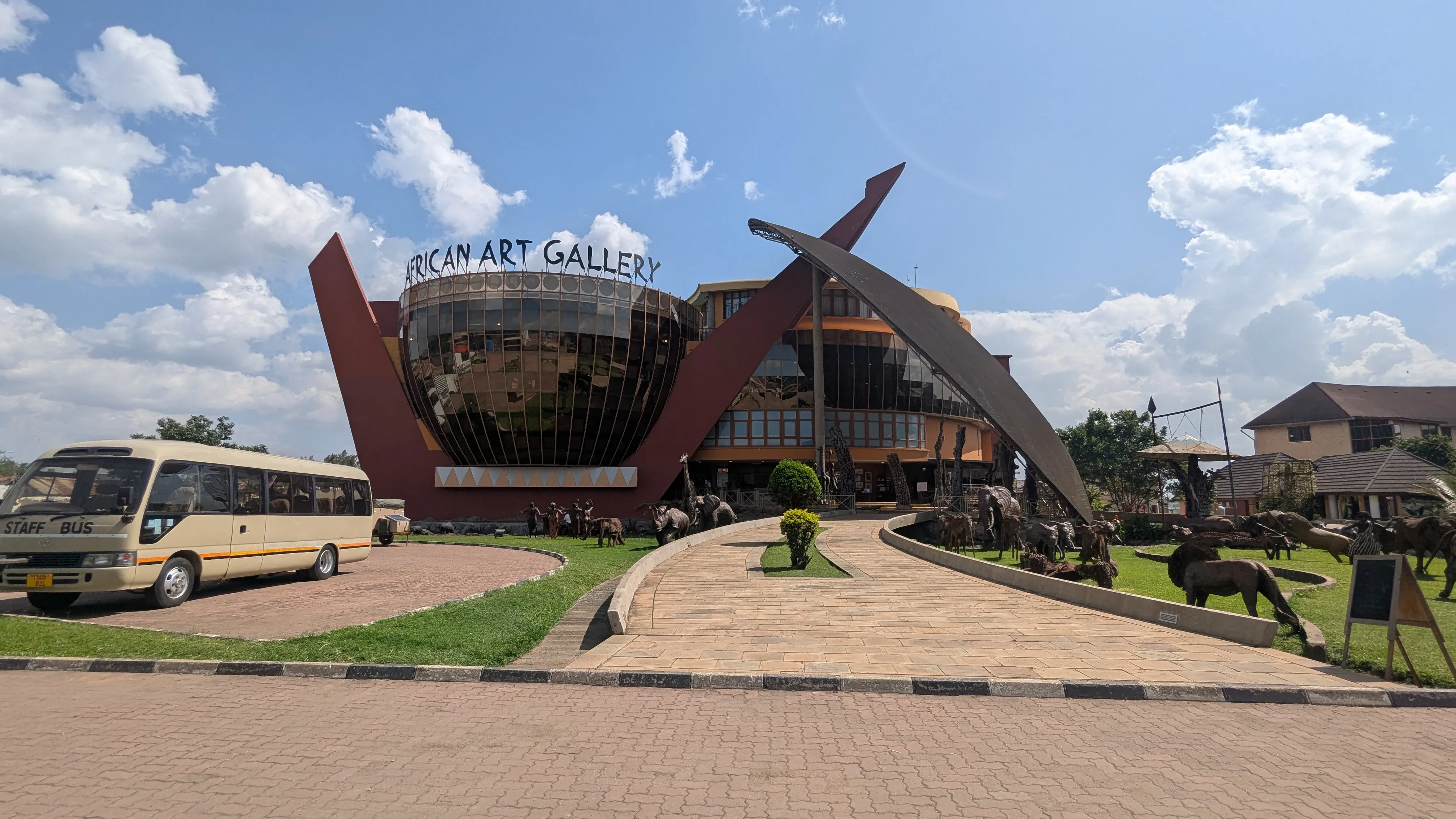 Budynek o nietypowym kształcie, z dużą ilością szkła i stalowymi elementami dekoracyjnymi. Na
budynku jest napis African Art Gallery. Przed budynkiem autobus, trawnik i drewniane figury
zwierząt na trawniku.