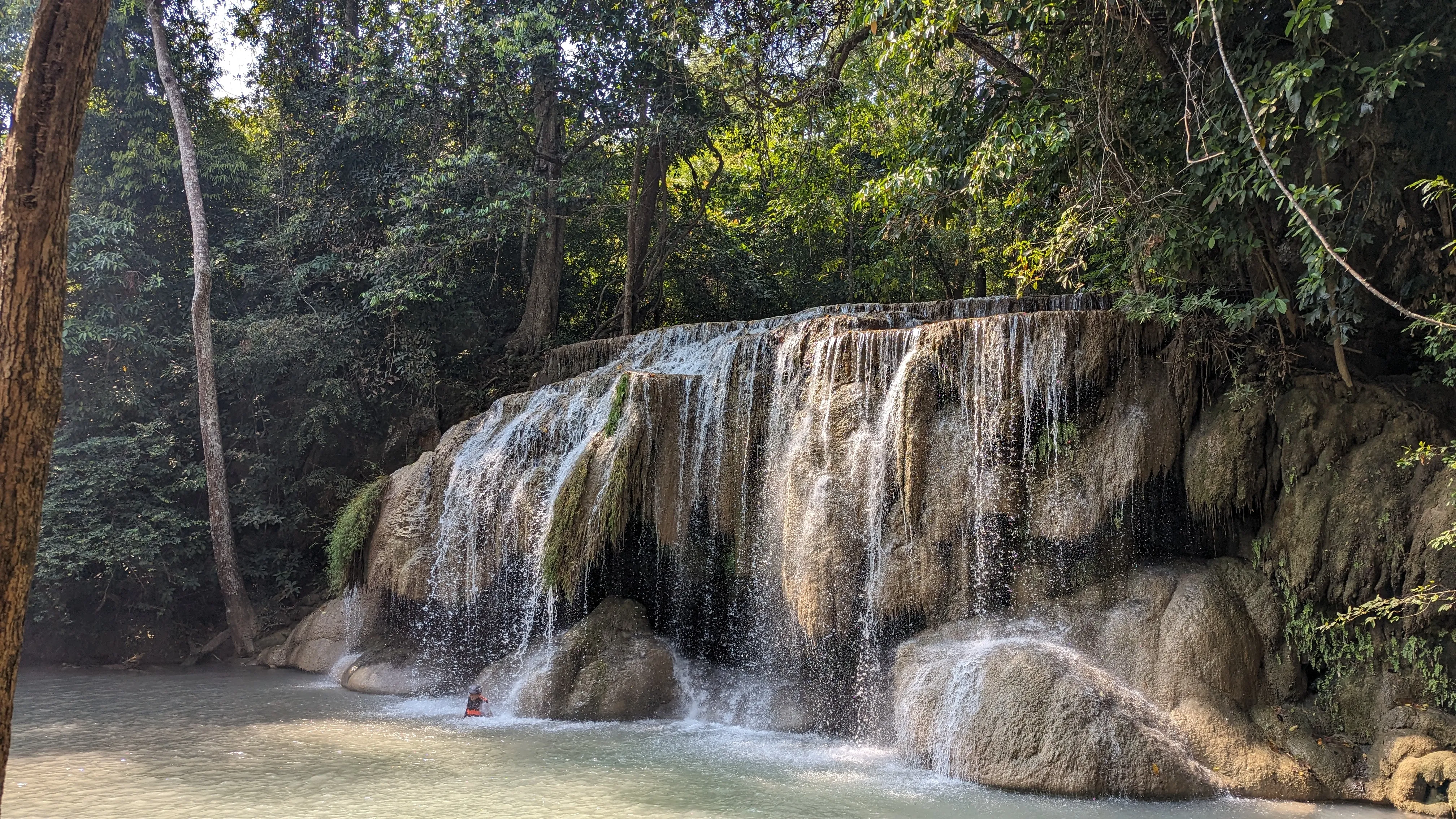 Szeroki wodospad, w jeziorze u dołu pływa osoba w kamizelce
ratunkowej