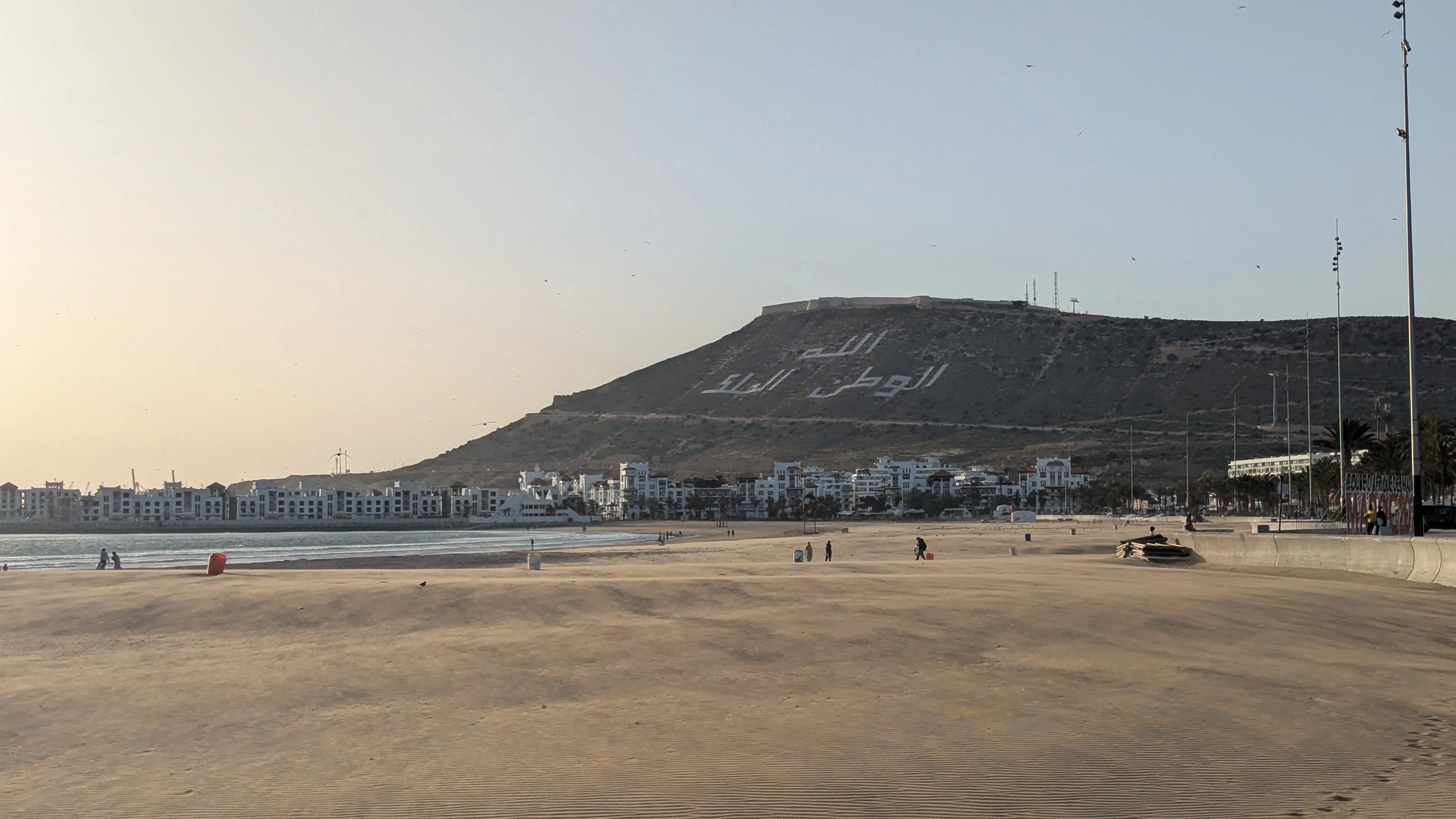 Plaża, a za nią wzgórze z napisem po arabsku