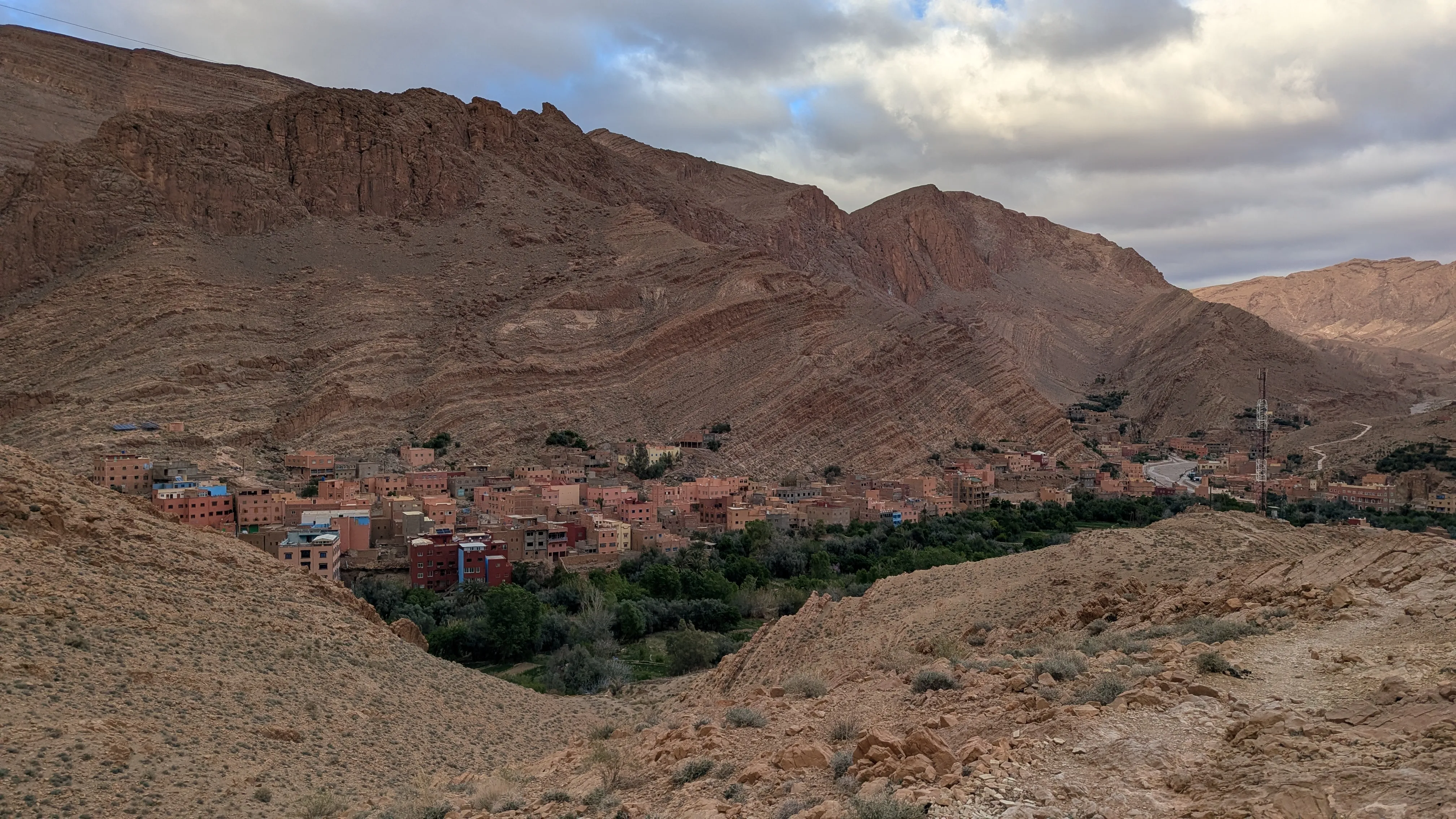W dolinie niskie budynki koloru otaczających ich skał, przed nimi zielone pola, na pierwszym
planie widać ścieżkę